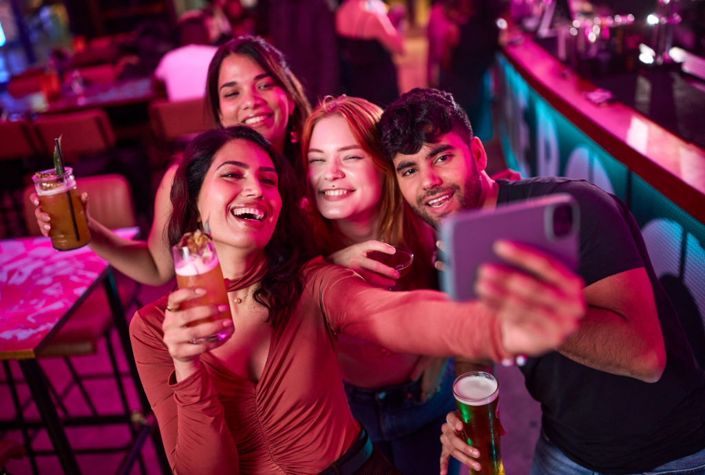 A group in a bar taking a selfie with drinks